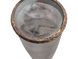 a glass with a liquid inside of it on a white surface