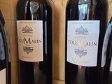 three bottles of red wine are lined up on a shelf