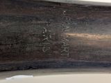 underside view of a baseball bat with a wooden handle on a white surface