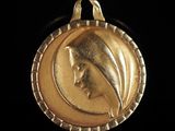 l'image d'une médaille d'or sur laquelle figure le visage d'une femme
