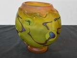 a yellow and green vase sitting on a black table