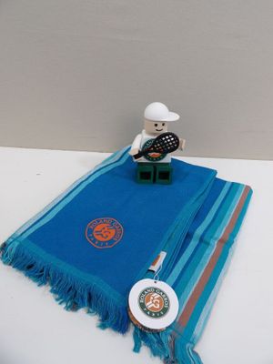 un ours en peluche assis sur une table, recouvert d'une couverture bleue