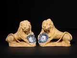 pair of lion figurines with blue and white plates on black background