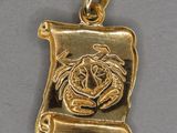 une image représentant un pendentif plaqué or orné d'un lion et d'un parchemin