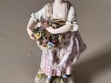 a figurine of a woman with a basket of flowers on a table