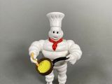 toy figurine of a chef holding a frying pan and a frying pan