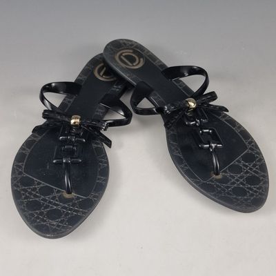 pair of black leather sandals with laces and bows on the toes