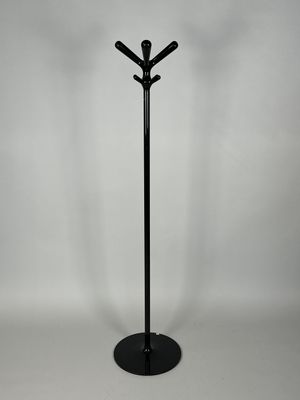 un porte-manteau en métal noir sur lequel sont accrochés trois manteaux