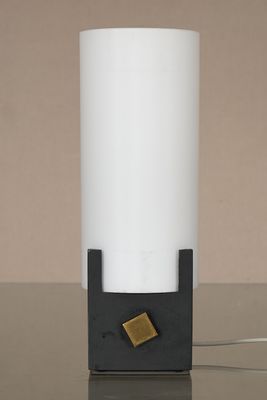 une lampe blanche avec un pied noir posée sur une table