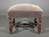 an antique foot stool with a purple upholstered cushion