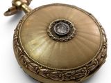 a gold pocket watch with a diamond in the center of it