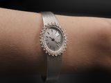 a woman ' s wrist with a silver watch on it
