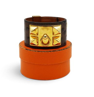 an orange leather bracelet with a gold buckle on top of it