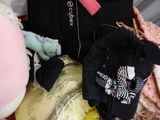 une valise noire sur laquelle sont posés des vêtements et une peluche