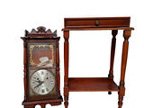 une petite table sur laquelle se trouve une horloge, à côté d'une autre petite table avec une étagère en dessous