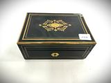 an old black and gold box with a gold decoration on the lid