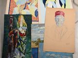 many paintings on a table with a cat in the background