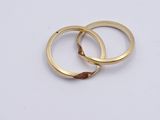 two gold wedding rings on a white surface