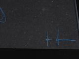 someone is writing on a piece of black paper with blue ink