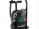 un aspirateur noir et vert muni d'un tuyau, sur fond blanc