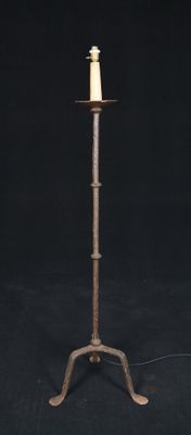 an old iron candle holder with a candle on it on a black background