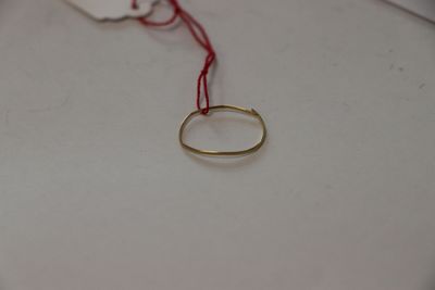 une bague en or à laquelle est attaché un cordon rouge