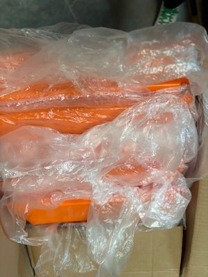 several carrots wrapped in plastic sitting on top of a cardboard box