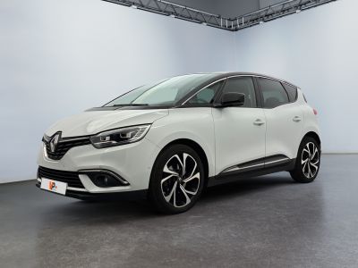 Une voiture blanche est garée dans une grande pièce.