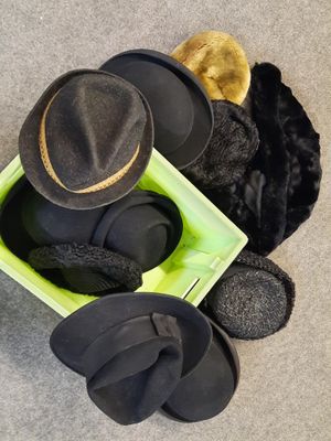several hats and mittens are sitting in a green box on the floor