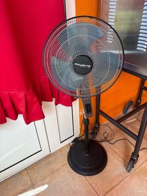 un ventilateur posé par terre devant une fenêtre