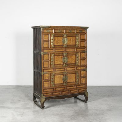 une commode ancienne avec des ferrures en laiton et des panneaux en bois
