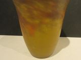 a yellow vase sitting on a table with a black wall behind it