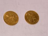 two gold coins sitting next to each other on top of a piece of paper