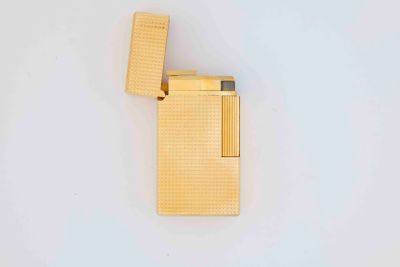 gold plated lighter on a white surface with a lighter in the middle