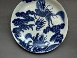 blue and white plate with a dragon on it on a table