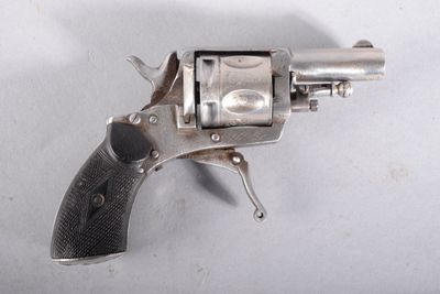 un revolver argenté posé sur une surface blanche, avec une crosse noire