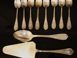 six silver spoons and a spatula on a black surface