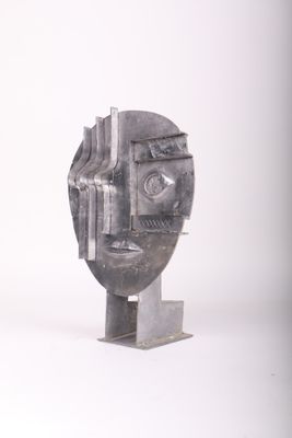 a metal sculpture of a man ' s face on a white surface