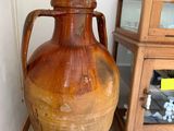 a large brown vase sitting next to a small wooden cabinet