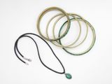 several bracelets and a necklace with a green stone on a white background