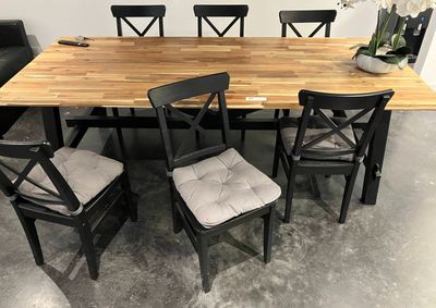 a wooden table with four chairs and a vase on it