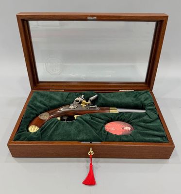 une boîte en bois contenant un pistolet et un pompon rouge