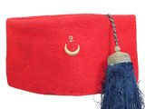 un bonnet rouge d'où pend un pompon bleu sur le côté