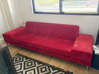 un canapé rouge dans un salon avec un tapis noir et blanc