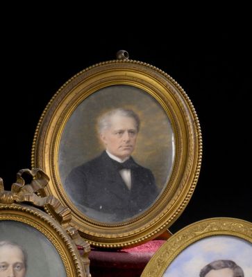 trois portraits encadrés d'hommes en costume-cravate posés sur une table