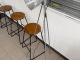 several stools are lined up against a wall with a lamp on it