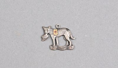 un gros plan d'un pendentif en métal en forme de chien sur une surface blanche