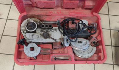 une boîte à outils contenant des outils, posée sur un sol carrelé