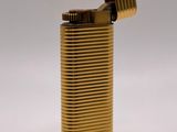 gold metal lighter on a white surface with a white background