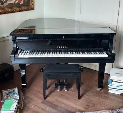 a black piano sitting in a living room next to a chair